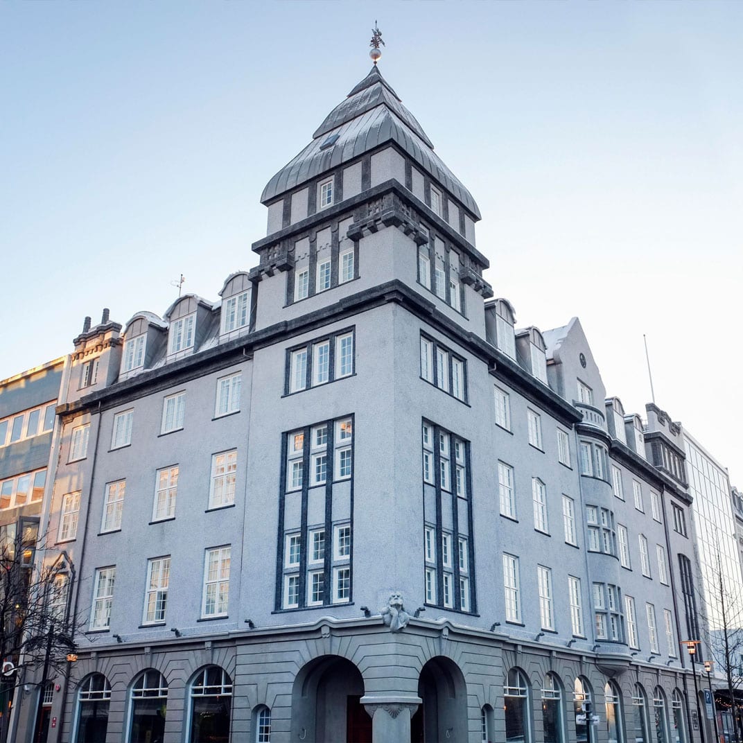 The grey corner facade and turret of Apotek Hotel in central Reykjavik at dusk