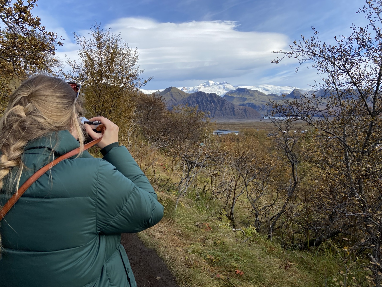 A traveler photographing the glacier across the autumn plain