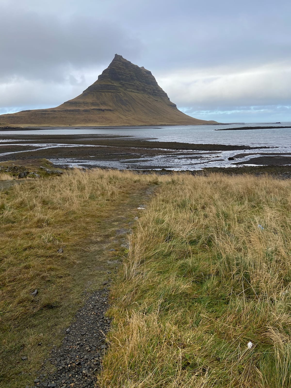 The pointed Kirkjufell mountain reflected in still water on Snaefellsnes