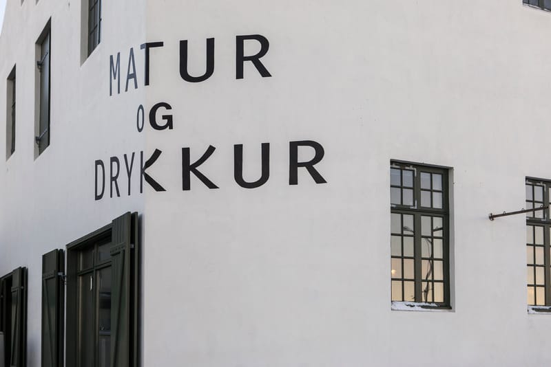 The white facade of Matur og Drykkur with its painted name