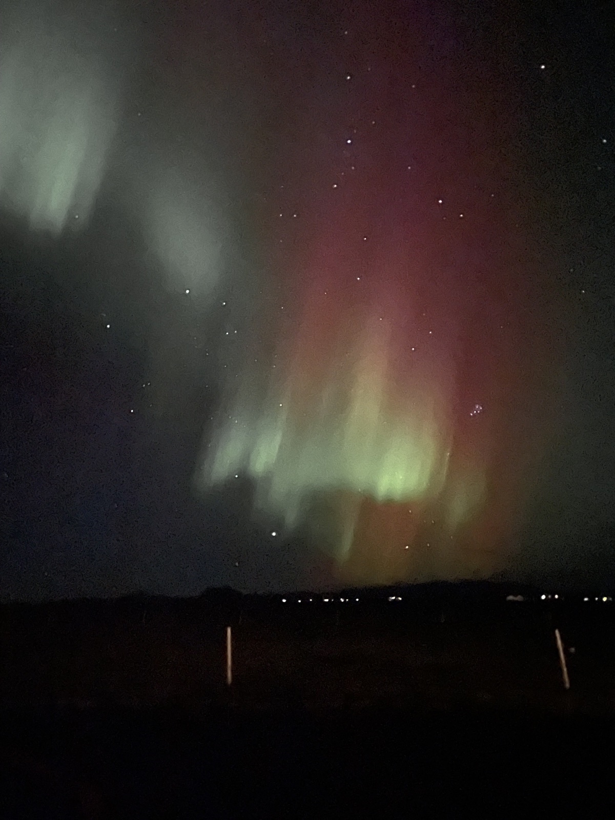Green and red northern lights over a flat dark field