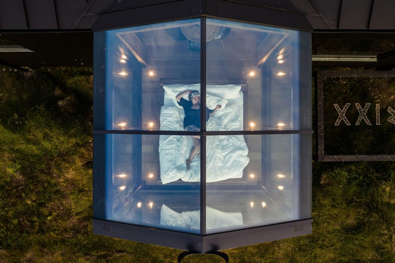 Aerial view of a glass-walled lodge with a bed open to the sky