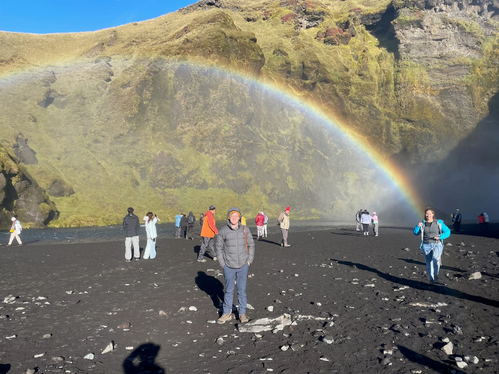 People standing in the rainbow at the foot of Skogafoss