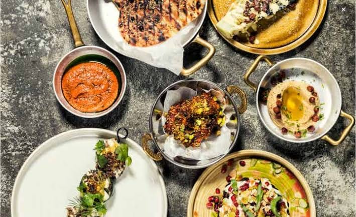 An overhead spread of Levantine sharing plates — grilled flatbread, hummus, dips, and small plates
