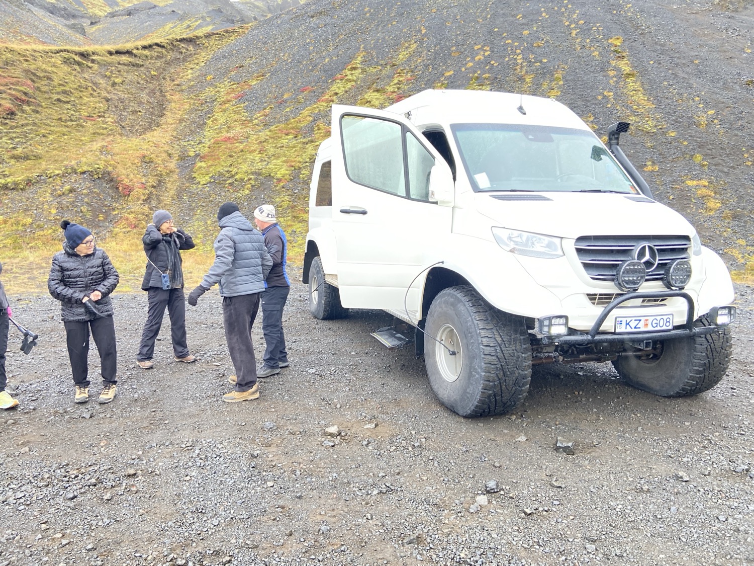 A white Mercedes super jeep on huge tires at a highland stop