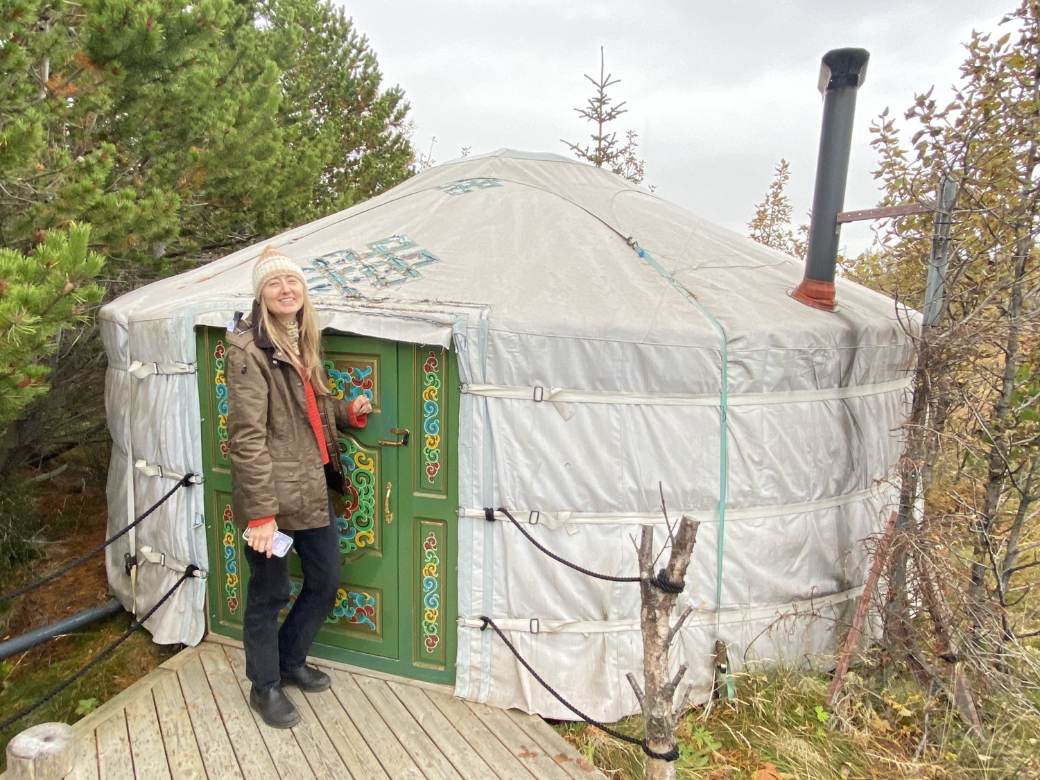 A canvas yurt with a painted green door among autumn trees