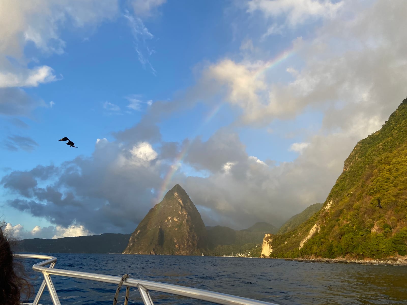 A rainbow arcing over a Piton, seen from the boat on the sunset sail